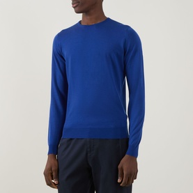 Model wearing John Smedley Lundy Extra Fine Knit Sweater in Mazarine Blue, crew neck, long sleeves, styled with dark navy trousers.