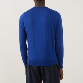 Model wearing John Smedley Lundy Extra Fine Knit Sweater in Mazarine Blue, back view, crew neck, ribbed trims, styled with navy trousers.