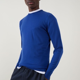 Model wearing John Smedley Lundy Extra Fine Knit Sweater in Mazarine Blue, styled with a white shirt and navy trousers.