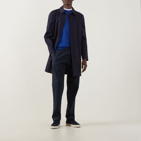 Model wearing John Smedley Lundy Extra Fine Knit Sweater in Mazarine Blue, styled with a navy mac coat and tailored trousers.