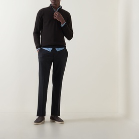 Model wearing John Smedley Tapton Extra Fine Knit Half-Zip Sweater in dark brown, styled with navy trousers and grey shoes.