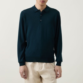 Model wearing John Smedley Belper Extra Fine Knit Polo Shirt in dark green, long sleeves, flat knit collar, styled with cream trousers