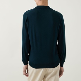 Model wearing John Smedley Belper Extra Fine Knit Polo Shirt in Dark Green, back view, with cream trousers.