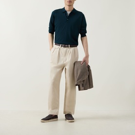 Model wearing John Smedley Belper Extra Fine Knit Polo Shirt in dark green, styled with cream wide-leg trousers and dark brown shoes