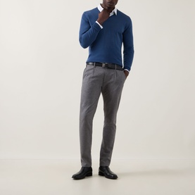 Model wearing John Smedley Blenheim Extra Fine Knit Sweater in Teal Firth, V-neck, styled with grey trousers and white shirt.