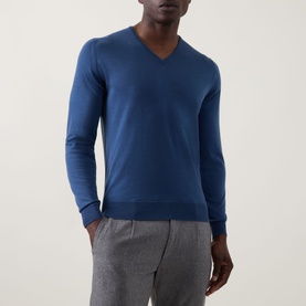 Model wearing John Smedley Blenheim Extra Fine Knit Sweater in Teal Firth, V-neck with ribbed trims, styled with grey trousers