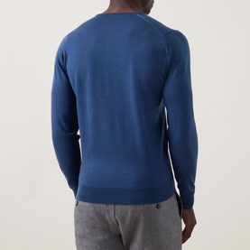 Model wearing John Smedley Blenheim Extra Fine Knit Sweater in Teal Firth, V-neck, long sleeves, ribbed trims, styled with grey trousers. Rear view.