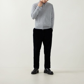 Model wearing John Smedley 16.Singular Extra Fine Knit Jacket in light grey with shawl collar and zip fastening, styled with black trousers and shoes.