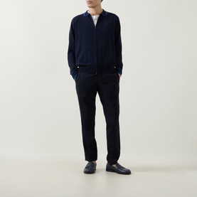 Model wearing John Smedley Albie Tipped Cardigan in navy, zip-through with flat collar, styled with black trousers and dark loafers.