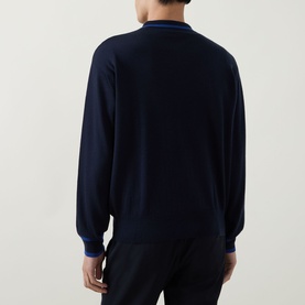 Model wearing John Smedley Albie Tipped Cardigan in navy, rear view showing long sleeves with contrast blue tipped ribbed cuffs and collar.