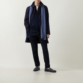 Model wearing John Smedley Albie Tipped Cardigan in navy, styled with a long dark coat, blue scarf and dark trousers.