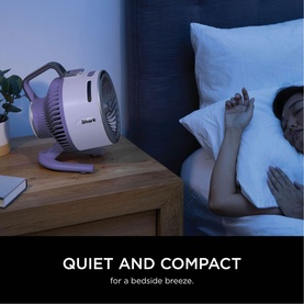 Shark FlexBreeze HydroGo Misting Fan in purple on a bedside table next to a sleeping person, with text "Quiet and Compact for a bedside breeze