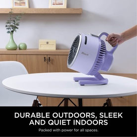 Shark FlexBreeze HydroGo Misting Fan in purple, placed on a white table indoors, shown being handled by a person's hand