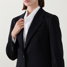 Model wearing Hugo Boss black wool coat with notched lapels and two-button fastening, styled with a white shirt underneath.