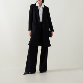 Model wearing Hugo Boss black wool coat, styled with wide-leg trousers and white shirt. Single-breasted, knee-length silhouette.