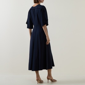 Model wearing Hugo Boss dark blue midi dress, rear view, featuring gathered sleeves, pleated skirt and V-neckline, styled with nude heels