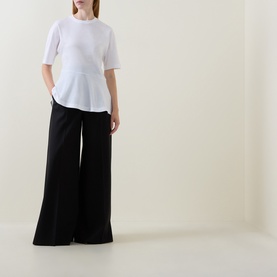 Model wearing Hugo Boss white cotton T-shirt with peplum hem, styled with wide-leg black trousers