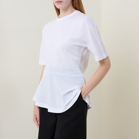 Model wearing Hugo Boss white cotton T-shirt with asymmetric peplum hem, styled with black wide-leg trousers