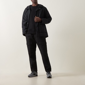 Model wearing Hugo black casual jacket with hood, styled with matching black trousers and grey trainers