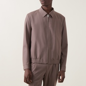 Model wearing Hugo Rust/Copper suit jacket with zip front, point collar, and elasticated hem, styled with matching trousers