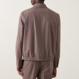 Model wearing Hugo Suit Jacket in Rust/Copper, rear view showing elasticated hem, styled with matching trousers