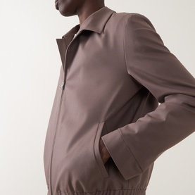 Model wearing Hugo Suit Jacket in Rust/Copper, zip-front with spread collar, hand resting in side pocket