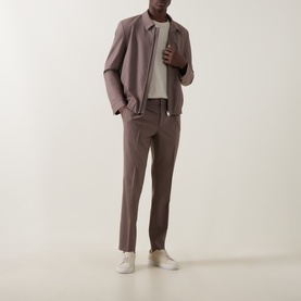 Model wearing Hugo Rust/Copper Suit Jacket with matching trousers, cream T-shirt, and white trainers.