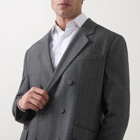 Model wearing Hugo dark grey suit jacket, double-breasted, styled with white shirt. Slim fit, notch lapels.