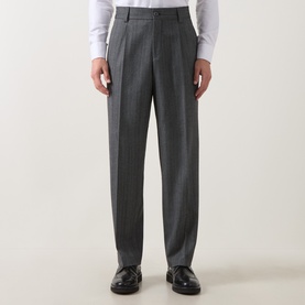 Model wearing Hugo dark grey suit trousers with pleat front and tapered leg, styled with white shirt and black loafers