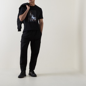 Model wearing Hugo black cotton T-shirt with graphic print, styled with black cargo trousers and chunky black boots.