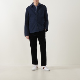 Model wearing Paul Smith navy cotton casual jacket with grey layered collar, styled with black trousers and white trainers.