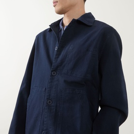 Model wearing Paul Smith navy cotton casual jacket with button fastening and chest pockets, layered over striped shirt.