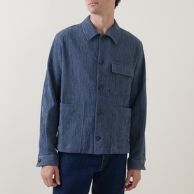 Model wearing Paul Smith Blue Casual Jacket in textured cotton, featuring chest patch pocket and dark buttons, styled with blue jeans