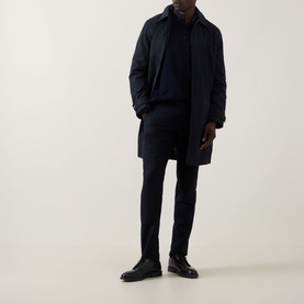 Model wearing Paul Smith Showerproof Car Coat in navy, styled with matching navy knitwear and trousers, and black leather shoes.