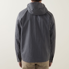 Model wearing Paul Smith grey casual jacket, rear view showing hood and lightweight shell fabric, styled with beige trousers
