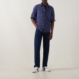 Model wearing Paul Smith navy casual shirt with dark indigo jeans and white leather trainers.