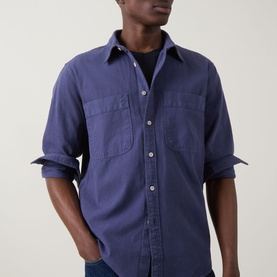 Model wearing Paul Smith navy casual shirt with dual chest pockets and button front, sleeves rolled to elbow, styled over black crew-neck tee