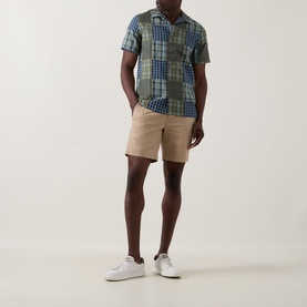 Model wearing Paul Smith Patchwork Check Shirt in green/navy with beige chino shorts and white trainers.
