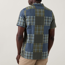 Model wearing Paul Smith Patchwork Check Shirt in green and navy, rear view showing patchwork check panels, short sleeves, paired with beige trousers.