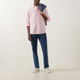 Model wearing Paul Smith pink casual shirt with blue jeans and white trainers, denim jacket draped over shoulder.