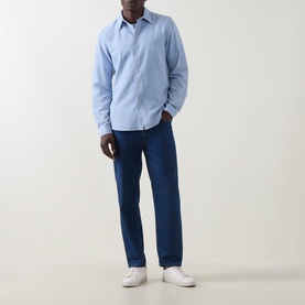 Model wearing Paul Smith Blue Single-Cuff Shirt with pointed collar, styled with dark blue jeans and white trainers.