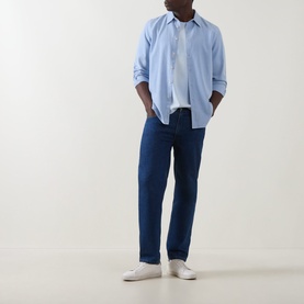 Model wearing Paul Smith Blue Single-Cuff Shirt with pointed collar, styled with dark indigo jeans and white trainers.