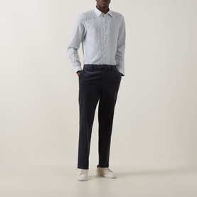 Model wearing Paul Smith white casual shirt with blue geometric print, styled with navy tapered trousers and white trainers.