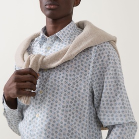 Model wearing Paul Smith white casual shirt with grey floral print, styled with a beige knit sweater draped over shoulders.