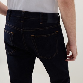 Model wearing Paul Smith Mid-Rise Slim Fit Tapered Leg Jeans in grey, rear view showing five-pocket detail and contrast stitching, styled with white