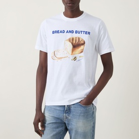 Model wearing Paul Smith Bread & Butter Logo T-Shirt in white with bread graphic print, styled with light wash blue jeans.