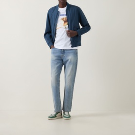 Model wearing Paul Smith Bread & Butter Logo T-Shirt in white, styled with a blue zip jacket, light wash jeans and green trainers.
