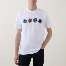 Model wearing Paul Smith white cotton crew neck T-shirt with multicoloured floral graphic print across chest, styled with dark jeans.