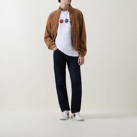 Model wearing Paul Smith white crew neck T-shirt with multicolour floral print, styled with tan suede bomber jacket and dark navy jeans.