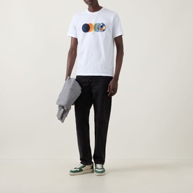 Model wearing Paul Smith Football Graphic Logo T-Shirt in white with black trousers and green trainers, holding a grey jacket.
